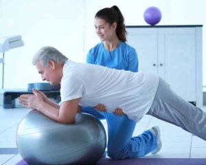 Man leaning on inflatable ball for physical therapy. Shoreside Interventional Pain, Sarasota, FL.